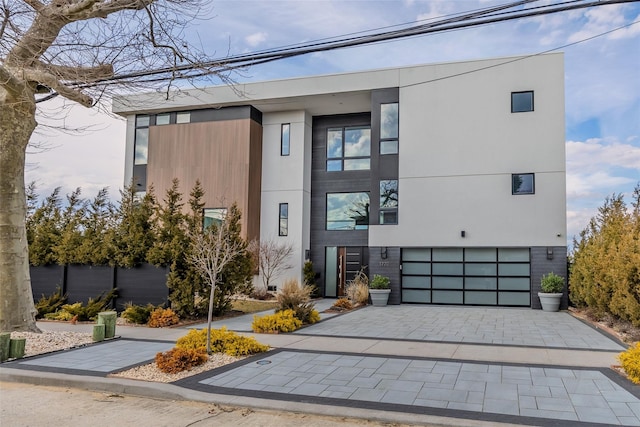 contemporary home featuring a garage, decorative driveway, and stucco siding