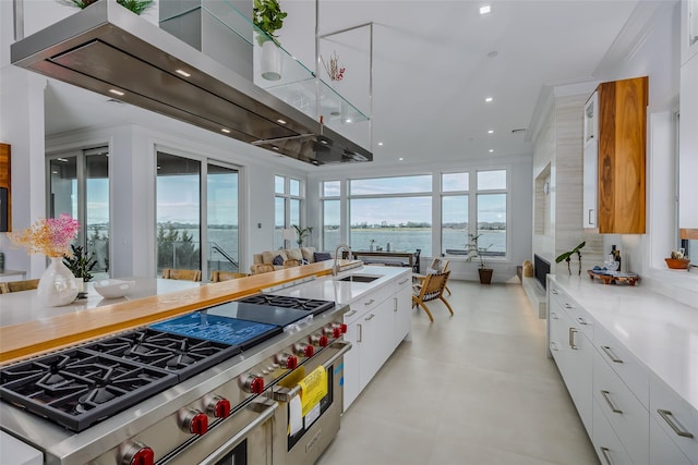 kitchen with range with two ovens, a water view, a sink, white cabinetry, and modern cabinets