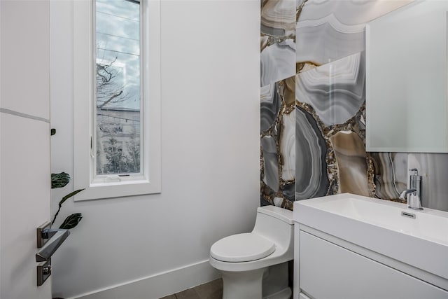 bathroom with baseboards, vanity, and toilet