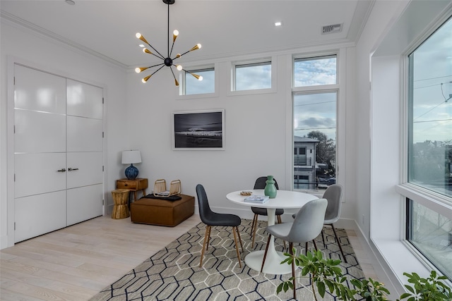 dining room with visible vents, baseboards, light wood-style flooring, crown molding, and a notable chandelier