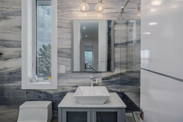 bathroom featuring a shower with shower door, vanity, and toilet