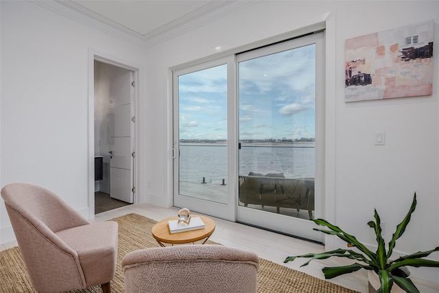 sitting room featuring a water view and crown molding