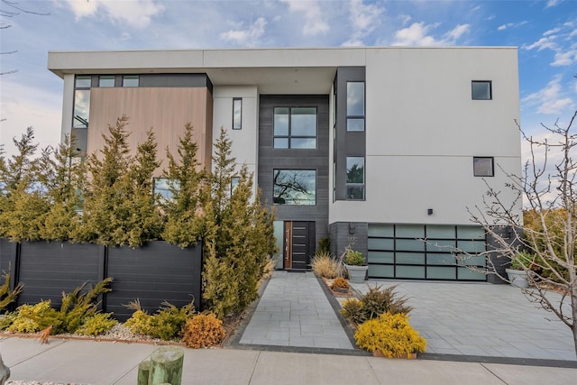 view of front of home with decorative driveway, stucco siding, and fence