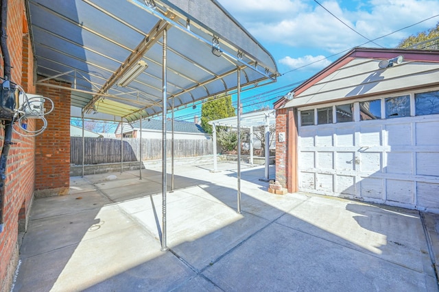 view of patio with an outdoor structure, concrete driveway, fence, and a garage