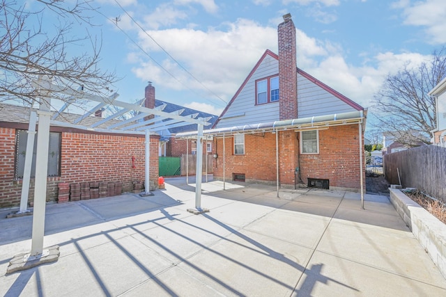 back of house with brick siding, a chimney, a patio, and fence