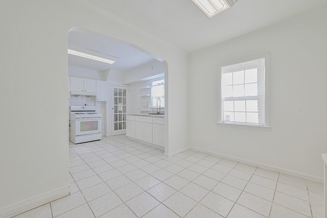 kitchen with under cabinet range hood, a sink, plenty of natural light, white gas range oven, and arched walkways