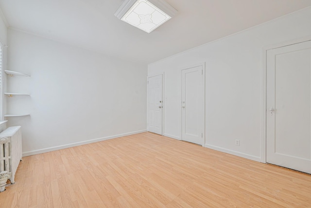 empty room featuring baseboards, wood finished floors, and radiator heating unit