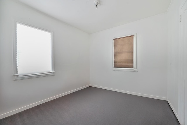 unfurnished room featuring dark carpet and baseboards