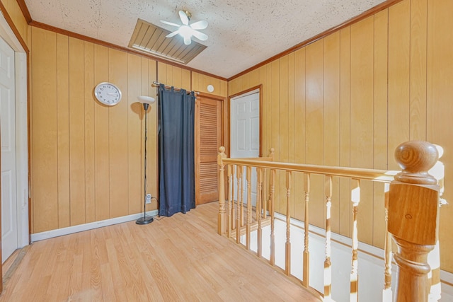 interior space featuring ornamental molding, wood walls, ceiling fan, and wood finished floors