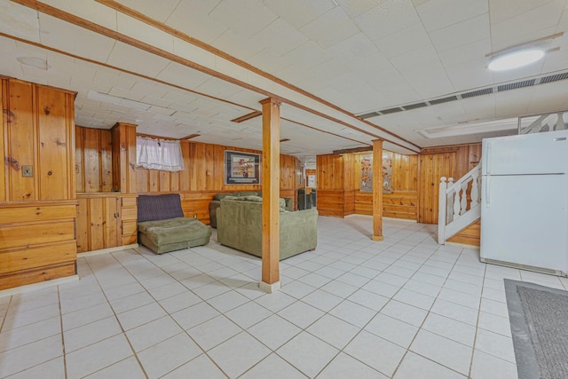 basement featuring stairway, wooden walls, and freestanding refrigerator