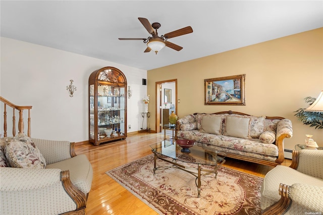 living area featuring a ceiling fan, light wood-type flooring, stairway, and baseboards