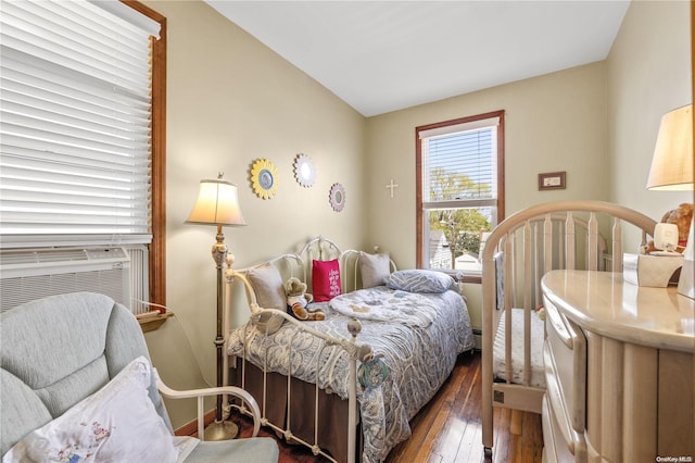 bedroom with baseboards, hardwood / wood-style flooring, vaulted ceiling, cooling unit, and a baseboard heating unit