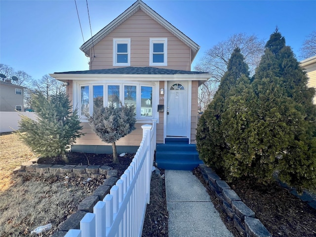 view of front of home with a shingled roof and fence