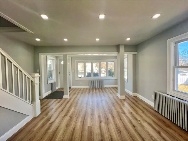 foyer entrance featuring stairs, radiator heating unit, and a wealth of natural light