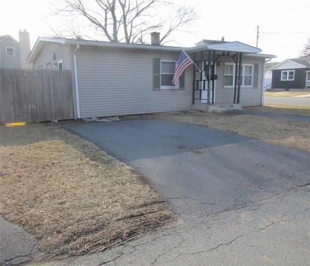 view of front of property with a front lawn, a chimney, fence, and aphalt driveway