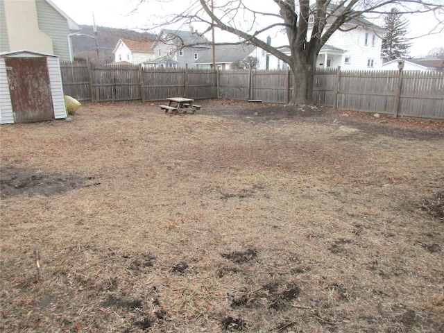 view of yard featuring a storage shed, a fenced backyard, and an outbuilding