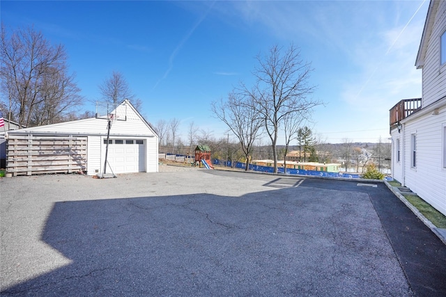 view of yard featuring aphalt driveway, a detached garage, an outbuilding, and a playground