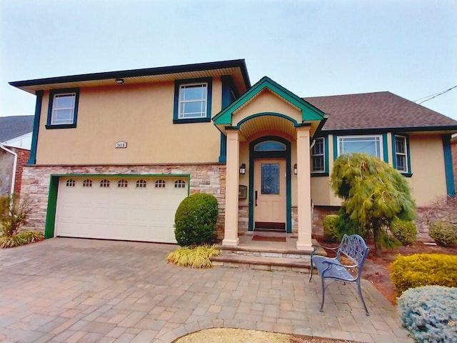 view of front of property featuring decorative driveway, stone siding, an attached garage, and stucco siding