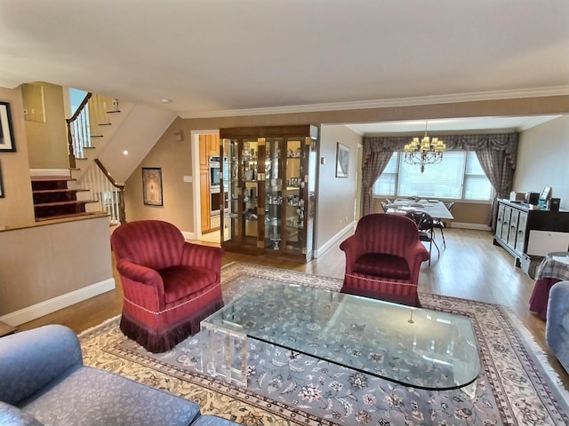 living area featuring an inviting chandelier, stairs, ornamental molding, and wood finished floors