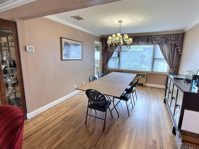 dining space with visible vents, crown molding, a notable chandelier, and wood finished floors