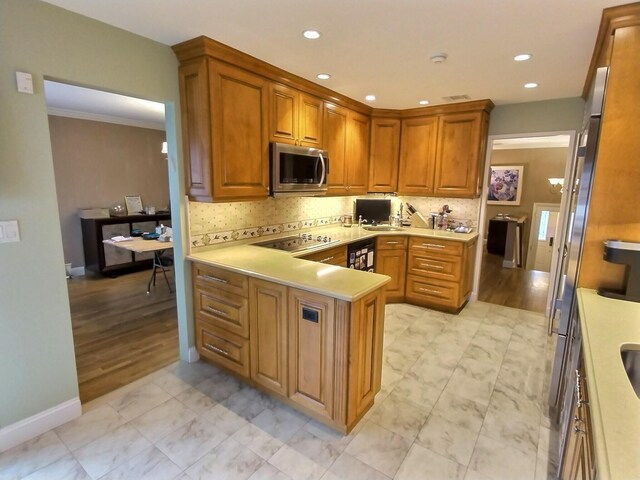 kitchen with light countertops, stainless steel microwave, backsplash, and black electric stovetop