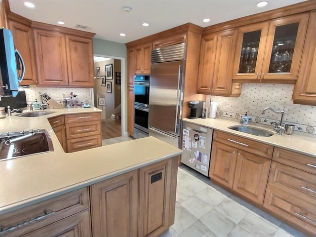 kitchen with stainless steel appliances, brown cabinetry, a sink, and light countertops