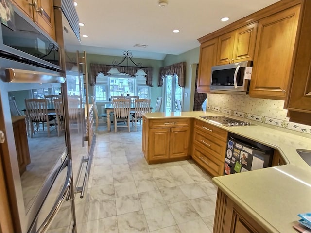 kitchen featuring cooktop, dishwashing machine, stainless steel microwave, and brown cabinets