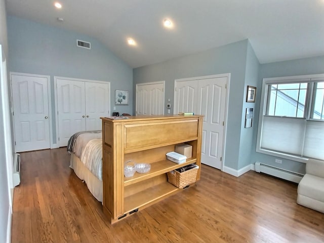 bedroom with visible vents, a baseboard radiator, dark wood-style flooring, vaulted ceiling, and two closets