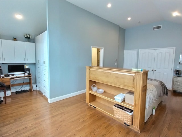 bedroom featuring high vaulted ceiling, light wood-type flooring, visible vents, and baseboards