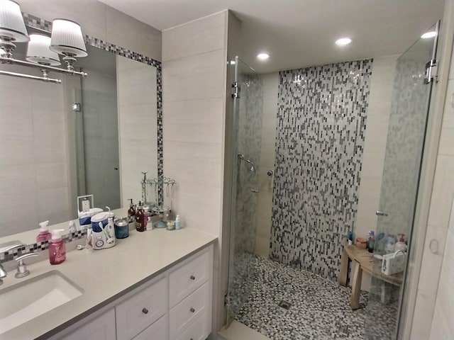 full bathroom with a shower stall, tile walls, and vanity