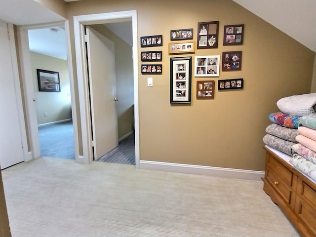 interior space with baseboards, lofted ceiling, and light colored carpet