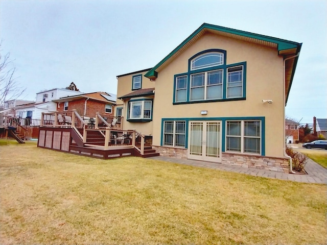 rear view of property featuring a yard, french doors, stairway, a wooden deck, and stucco siding