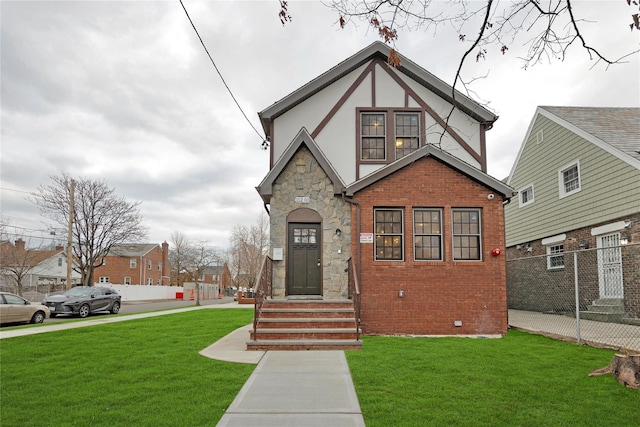 tudor home with brick siding, a front lawn, stucco siding, crawl space, and stone siding