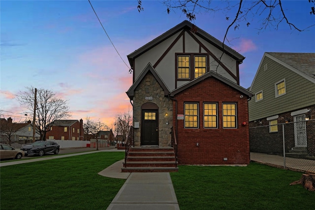 english style home with brick siding, stucco siding, a yard, crawl space, and stone siding