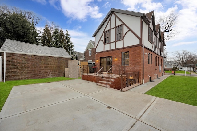 back of property featuring a yard, brick siding, and stucco siding