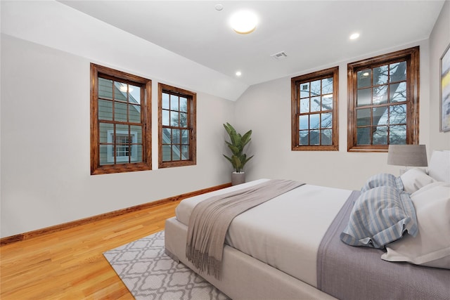 bedroom featuring visible vents, baseboards, wood finished floors, and vaulted ceiling