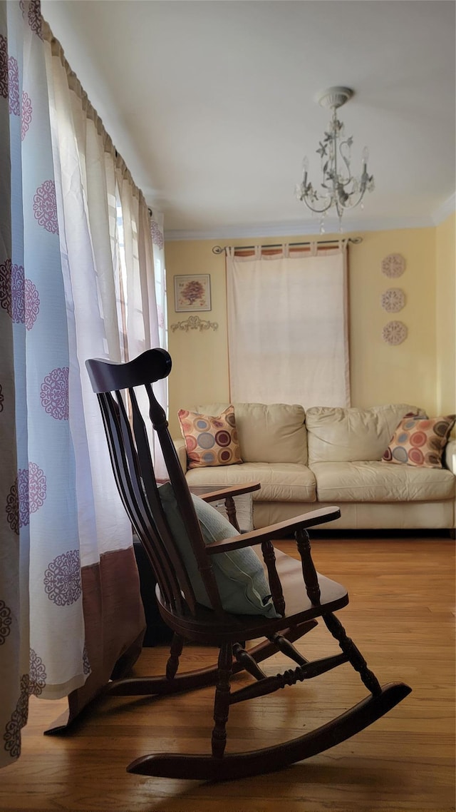 living area featuring ornamental molding, wood finished floors, and a chandelier