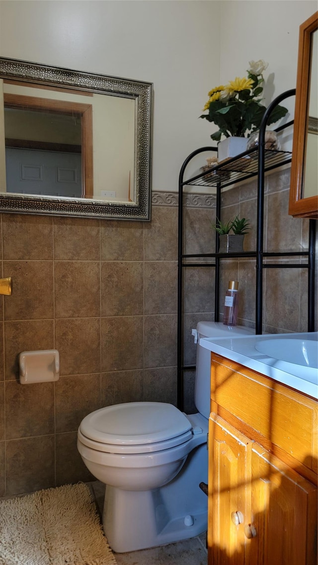 bathroom with toilet, tile walls, and vanity