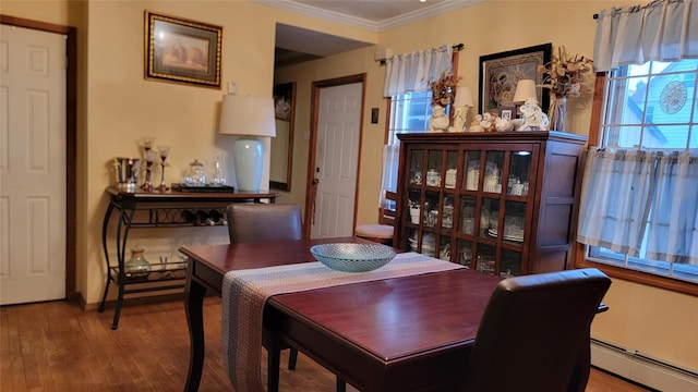 dining room with a baseboard heating unit, a healthy amount of sunlight, wood finished floors, and ornamental molding