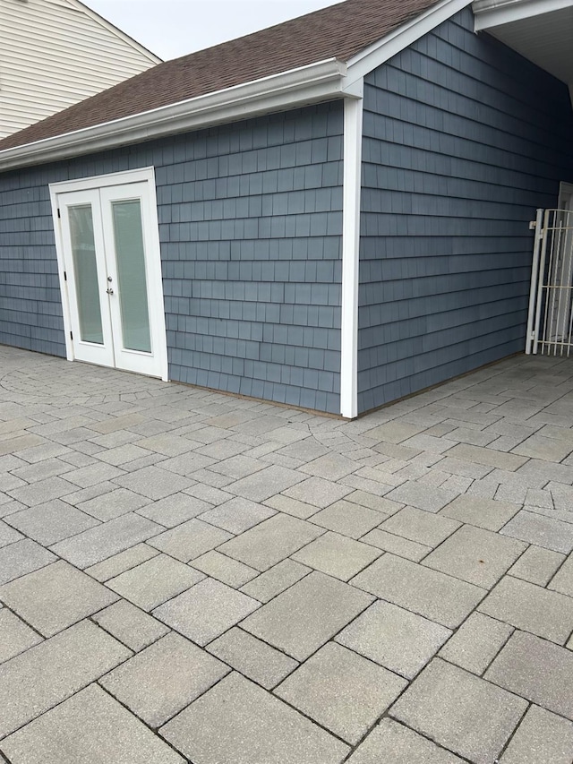 exterior space featuring roof with shingles, a patio, and french doors