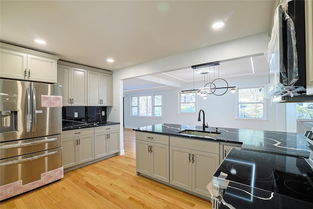 kitchen featuring plenty of natural light, stainless steel refrigerator with ice dispenser, light wood finished floors, and a sink