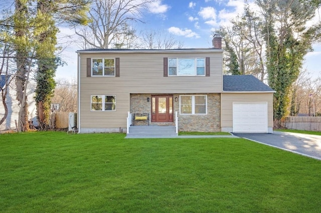 colonial-style house with aphalt driveway, a garage, stone siding, a front lawn, and a chimney