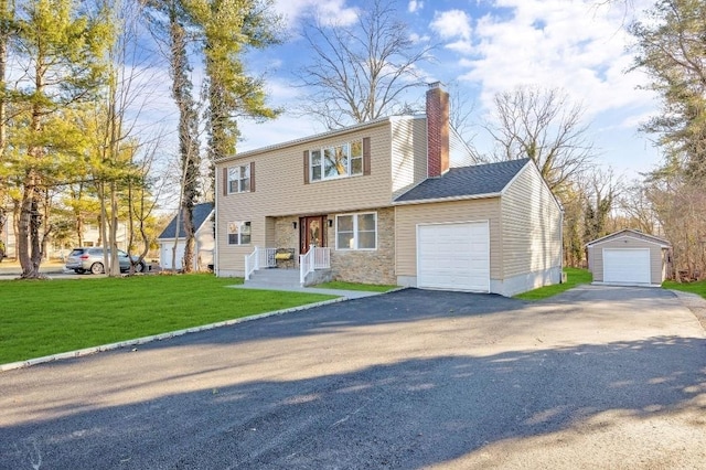 colonial house featuring driveway, stone siding, a chimney, and a front yard