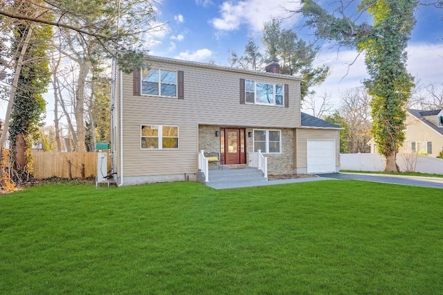 colonial home with aphalt driveway, an attached garage, fence, and a front yard