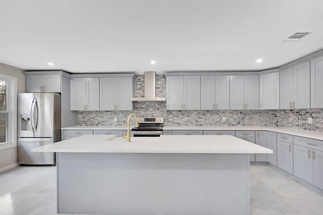 kitchen with stainless steel appliances, light countertops, gray cabinets, wall chimney exhaust hood, and tasteful backsplash