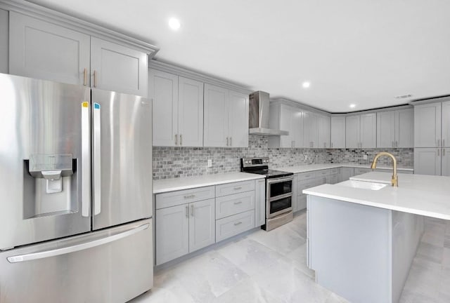 kitchen with stainless steel appliances, a sink, wall chimney range hood, backsplash, and gray cabinets