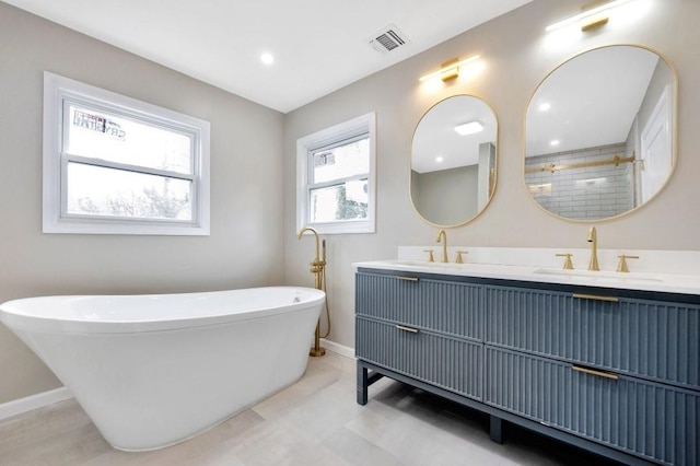 bathroom featuring a freestanding bath, double vanity, a sink, and visible vents