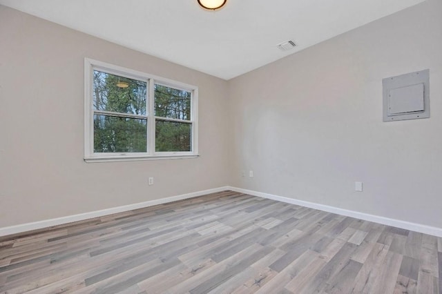 spare room with light wood-type flooring, visible vents, and baseboards