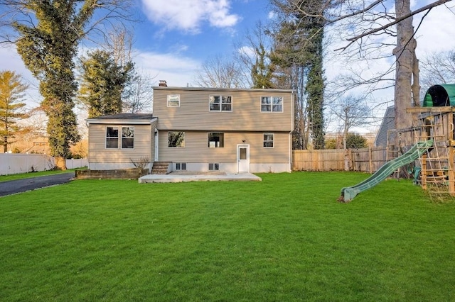 back of house featuring entry steps, a playground, fence, a lawn, and a chimney