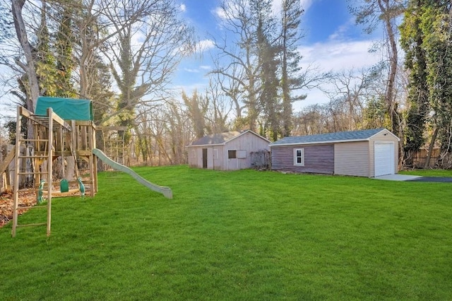 view of yard with a garage, a playground, and an outdoor structure